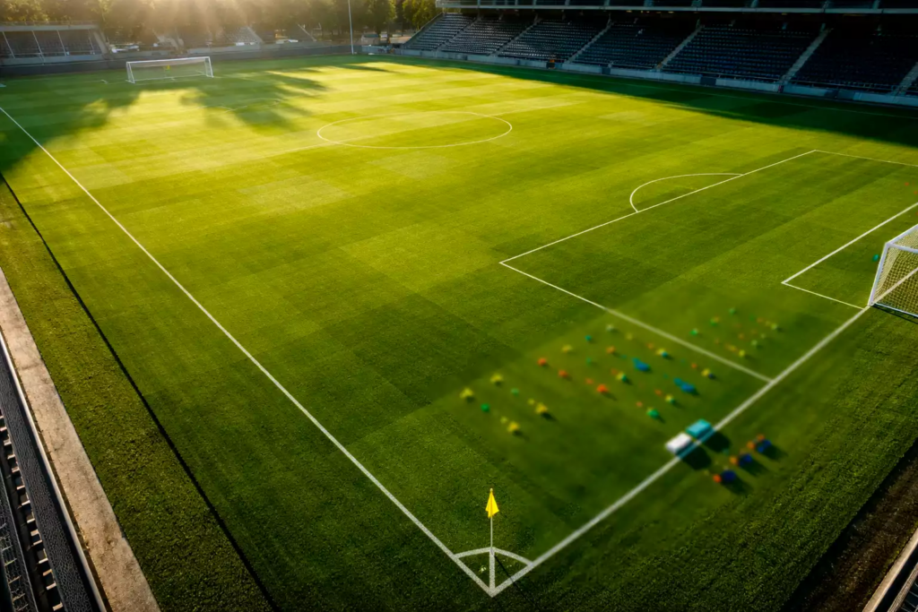 Campo di calcio verde con linee bianche visto dall'alto durante allenamento